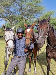 a man is standing between two horses at Dolly Farm & River Camp, Luxury Tents in Usa River