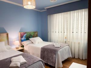 a bedroom with two beds and a blue wall at A DE NENO in Melide