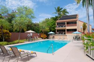 a swimming pool with chairs and a building at The Kona Billfisher in Kailua-Kona