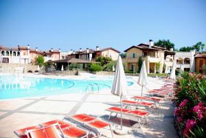 a row of chairs and umbrellas next to a swimming pool at Sakura House By Bookinggardalake in Moniga