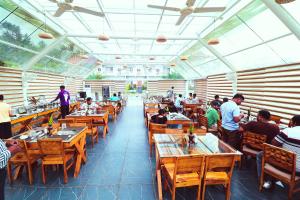 a restaurant with wooden tables and people sitting at tables at Advaya Luxury Resort, Sakleshpur in Sakleshpur