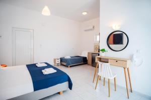 a white bedroom with a bed and a mirror at Fardini Resorts in Kavos