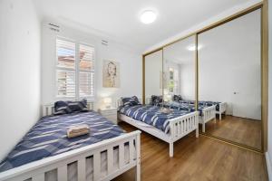 two beds in a room with mirrors at Fairlight Luxe Escape 4BR with Parking in Killara