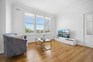 a living room with a chair and a television at Fairlight Luxe Escape 4BR with Parking in Killara