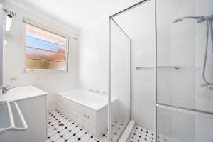 a white bathroom with a shower and a sink at Fairlight Luxe Escape 4BR with Parking in Killara +9 photos