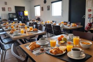 a row of tables with breakfast foods and orange juice at Enzo Hotels Chartres Mainvilliers in Chartres