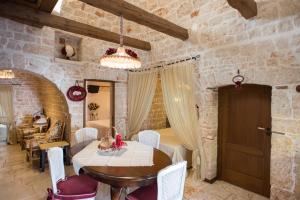a dining room with a wooden table and white chairs at Romantic Trulli in Alberobello