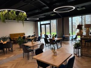 a restaurant with wooden tables and chairs and windows at Eco Nieborów in Nieborów