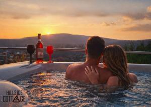 a man and woman sitting in a hot tub with a bottle of wine at Hillside Cottage in Pécs