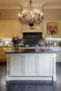 a kitchen with white cabinets and a chandelier at Bed & Boterham Carpediem in Hamont