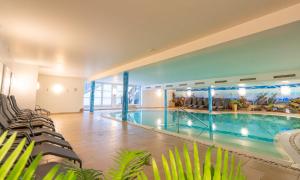 a large swimming pool in a building with chairs at Grafenberg Resort by Alpeffect Hotels in Wagrain