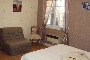 a bedroom with a bed and a chair and a window at le moulin à vent in Céré-la-Ronde
