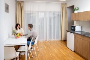 a man and woman sitting at a table in a kitchen at Nyíltvízi Edzőközpont in Dunakeszi