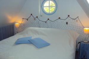 a white bed with two blue pillows on it at le moulin à vent in Céré-la-Ronde