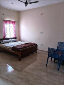 a bedroom with a bed and a chair and a window at Kalpatharu Sprit Boarding and Lodging in Sivaganga