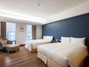 a hotel room with two beds and a chair at Tempus Hotel in Taichung +174 photos