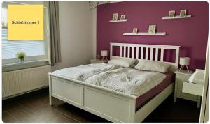 a bedroom with a white bed with a purple wall at Huus Negen in Neuharlingersiel
