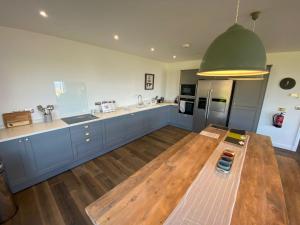 a large kitchen with blue cabinets and a green ceiling at Porthdinllaen by Together Travel - Luxury 5-Bed Holiday Retreat in Pistyll