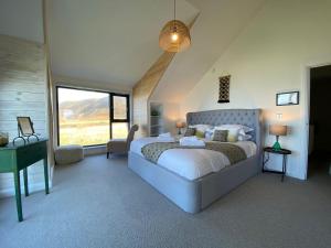 a bedroom with a bed and a desk and a window at Porthdinllaen by Together Travel - Luxury 5-Bed Holiday Retreat in Pistyll