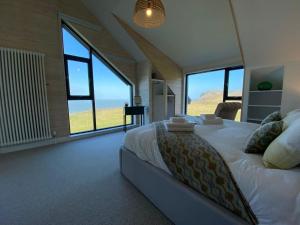 a bedroom with a large bed with large windows at Porthdinllaen by Together Travel - Luxury 5-Bed Holiday Retreat in Pistyll +18 photos
