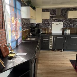 a kitchen with black counters and white cabinets at La Clef d'Or in Magescq +9 photos