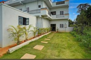 a large white building with plants in a yard at Kalpatharu Sprit Boarding and Lodging in Sivaganga