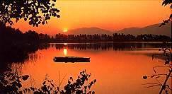 a lake with a boat in the water at sunset at Gasthof SONNE in Seehausen am Staffelsee