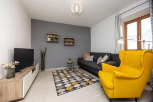 a living room with a couch and a yellow chair at Ferienhaus Karin in Cortaccia