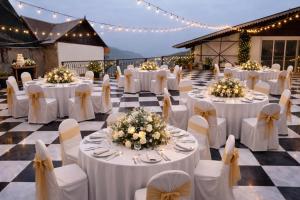 a banquet hall with white tables and chairs and lights at Cochrane Place By Teesta Hotels in Kurseong