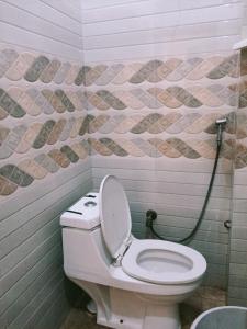 a white toilet in a bathroom with a mosaic wall at Hotel Sasa Paradise in Lucknow