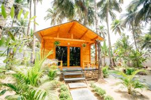 a wooden cabin in the middle of palm trees at The Pearl Beach Resort in Canacona