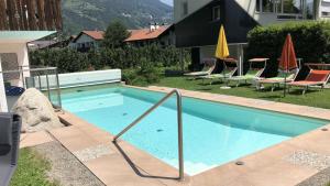 a swimming pool in a yard with chairs and umbrellas at Garni Franz Leiter in Lagundo