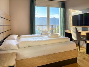 a bedroom with two beds and a large window at Adlerblick Deluxe Seeblick Ossiacher See in Annenheim
