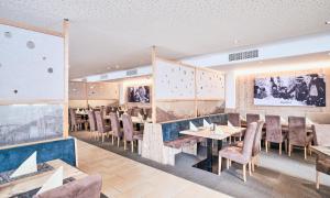 a restaurant with tables and chairs in a room at Grafenberg Resort by Alpeffect Hotels in Wagrain