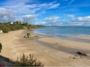 a beach with people walking on the sand and the water at Luxury Georgian Townhouse Tenby Sleeps 8 Parking Permit in Tenby