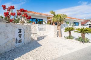 a house with a stone wall and palm trees at 蒼望楼 in Kamogawa