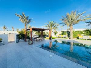 a swimming pool with a gazebo and palm trees at Villa el Kasbah in Midoun