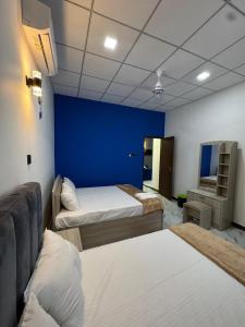 a room with two beds and a blue wall at Muthugala Resort in Anuradhapura