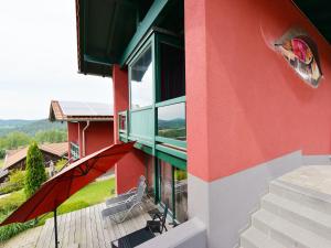 a red building with a balcony with an umbrella at Rosy Holiday Home in Blossersberg with Private Terrace in Viechtach