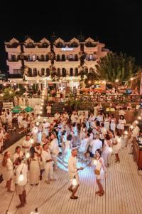 a large group of people dancing in front of a building at The Diplomat Hotel in Turunç +195 photos