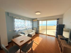 a living room with a couch and a table and a television at Meduse Seafront - Attico al Mare in Torvaianica