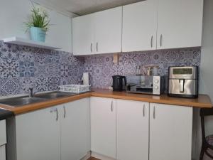 a kitchen with white cabinets and a microwave at Melrose Garden Cottages - Hibiscus Cottage in Durban