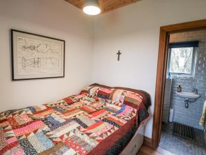 a bedroom with a quilt on a bed with a sink at Bosca Neadu in Dingle