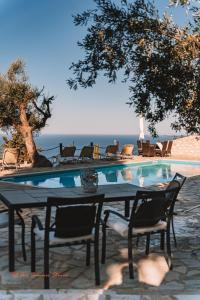 a table and chairs next to a swimming pool at Sunset View Studios in Agios Nikitas