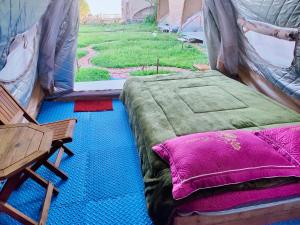 a bed and a chair in a tent at Bamboo Glamping Tà Xùa in Bắc Yên