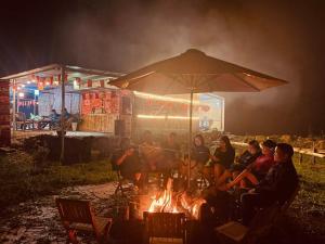 a group of people sitting around a fire at night at Bamboo Glamping Tà Xùa in Bắc Yên