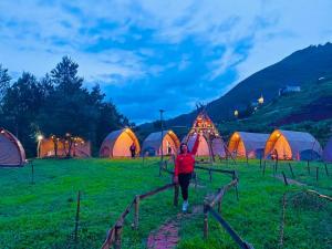 a person walking in front of a group of tents at Bamboo Glamping Tà Xùa in Bắc Yên +69 photos