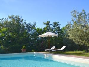カスティリオーン・フィオレンティーノにあるCharacteristic cottage in the Tuscan hillsのパラソルと椅子2脚付きのプールを提供しています。