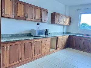 a kitchen with wooden cabinets and a microwave at Diani Exquisite 3BR in Ukunda