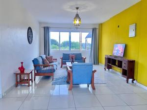 a living room with blue chairs and a yellow wall at Diani Exquisite 3BR in Ukunda